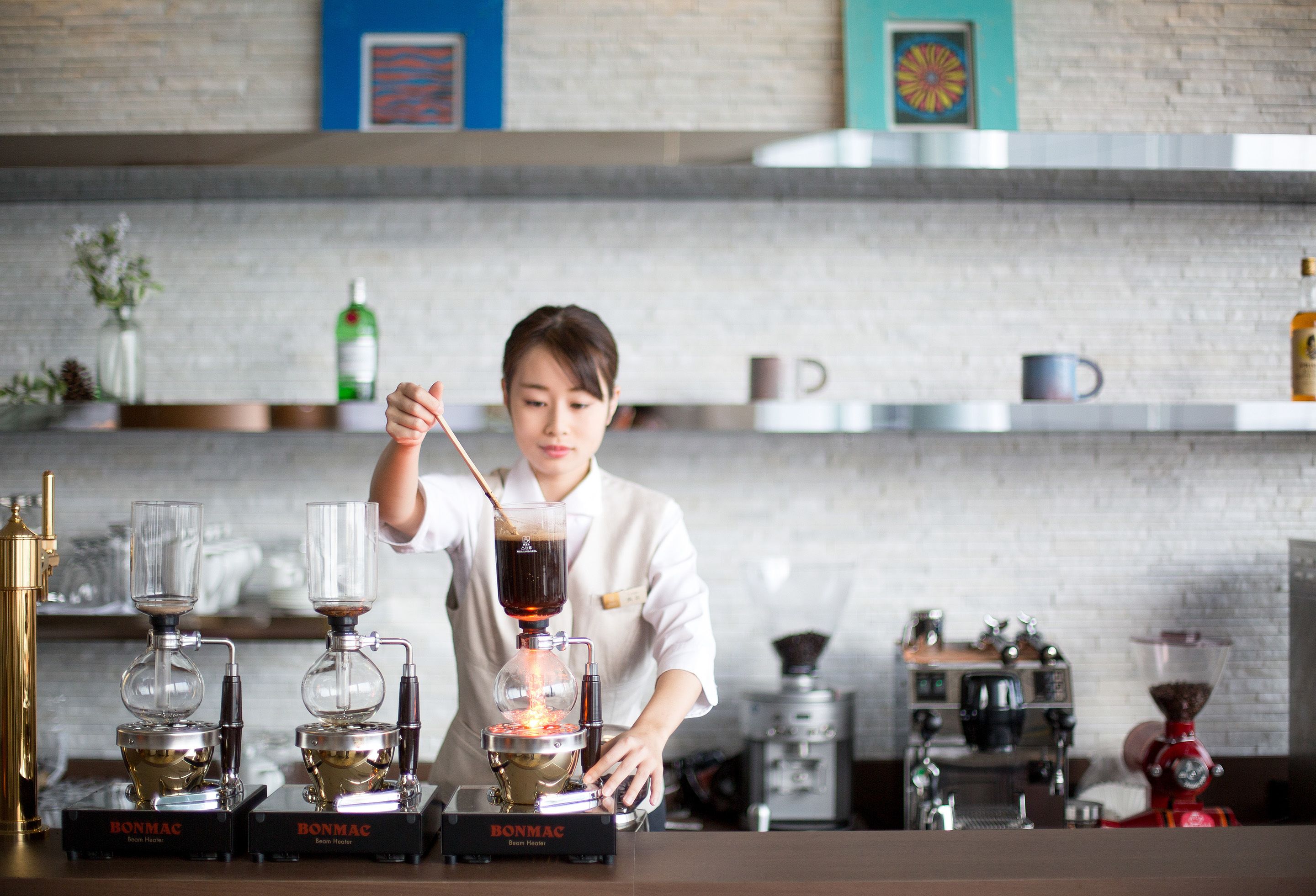 A barista working with coffee machines, likely in a café or restaurant setting.