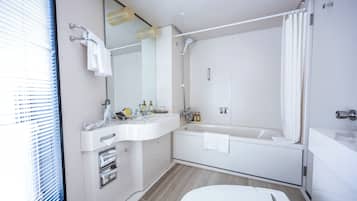 A modern bathroom with a white sink, mirror, and bathtub.