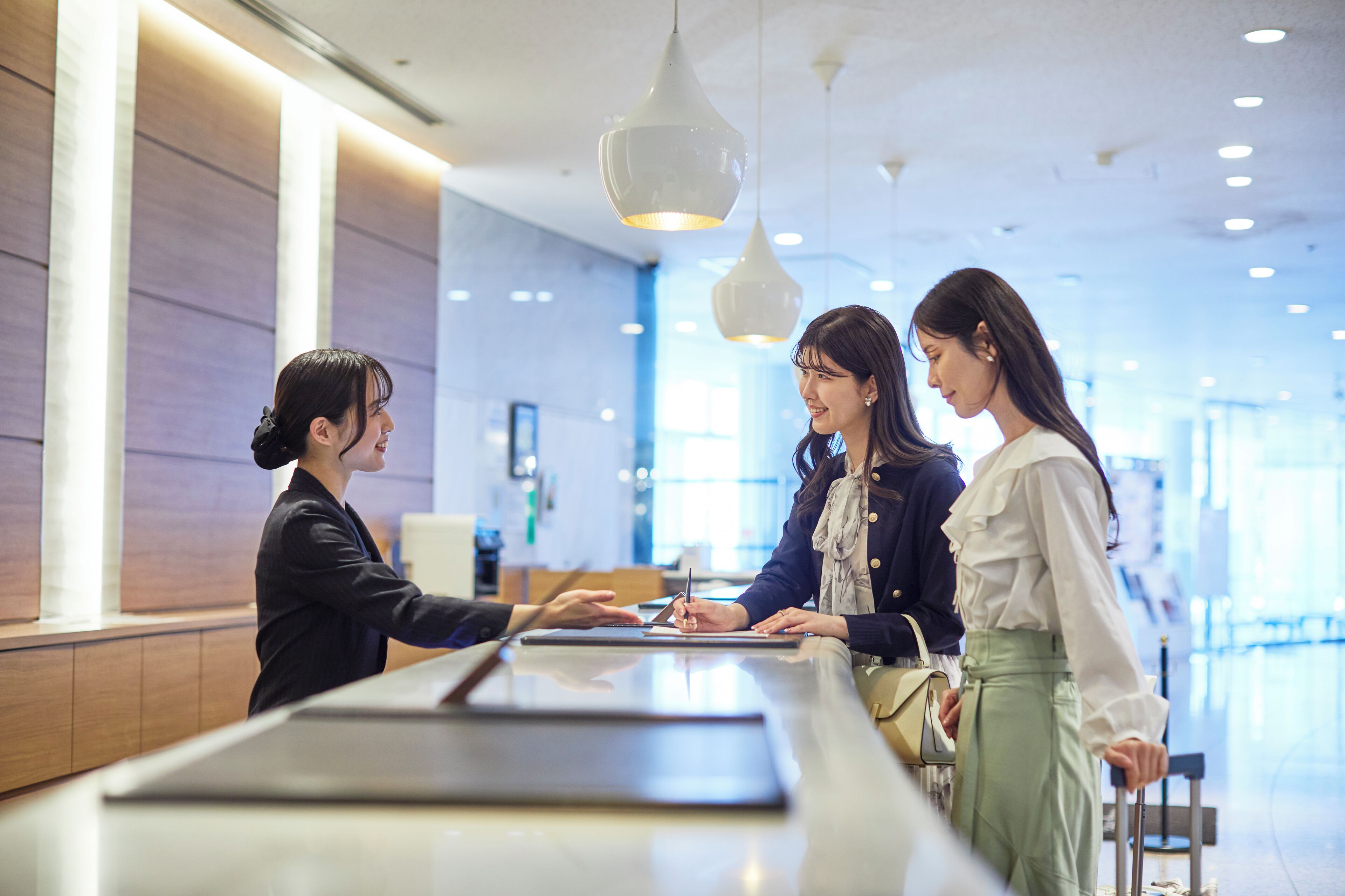 A reception area with a counter, modern pendant lighting, and a spacious interior.