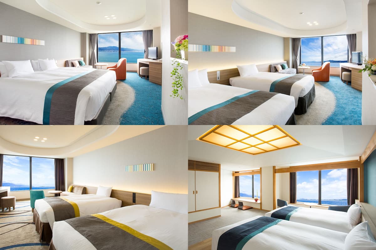 A hotel room with two beds, a desk, a chair, and a view of the sea.