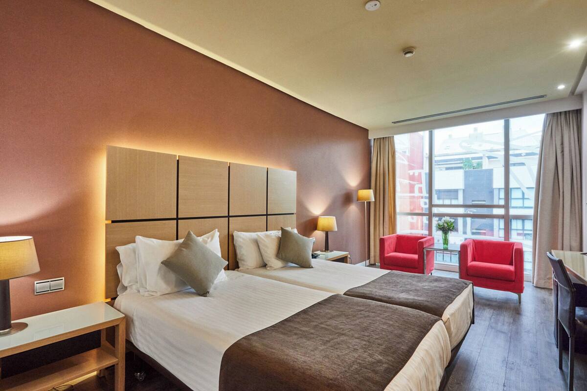 Een hotelkamer met een groot bed, twee nachtkastjes, een bureau en een stoel.
