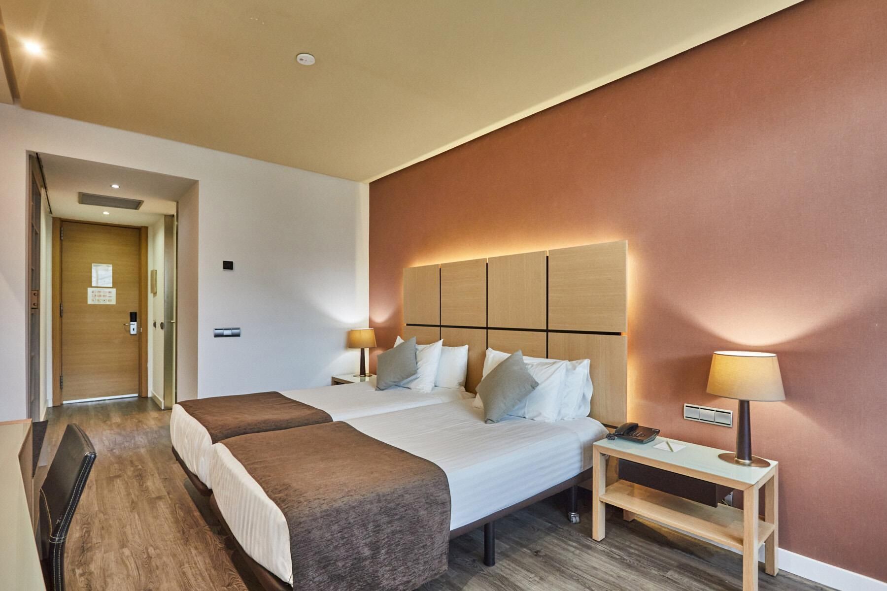 A hotel room with a large bed, two bedside tables, a desk, and a chair.