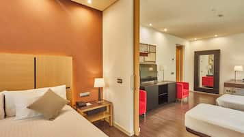 Een hotelkamer met een bed, nachtkastje, lamp en een rode stoel.