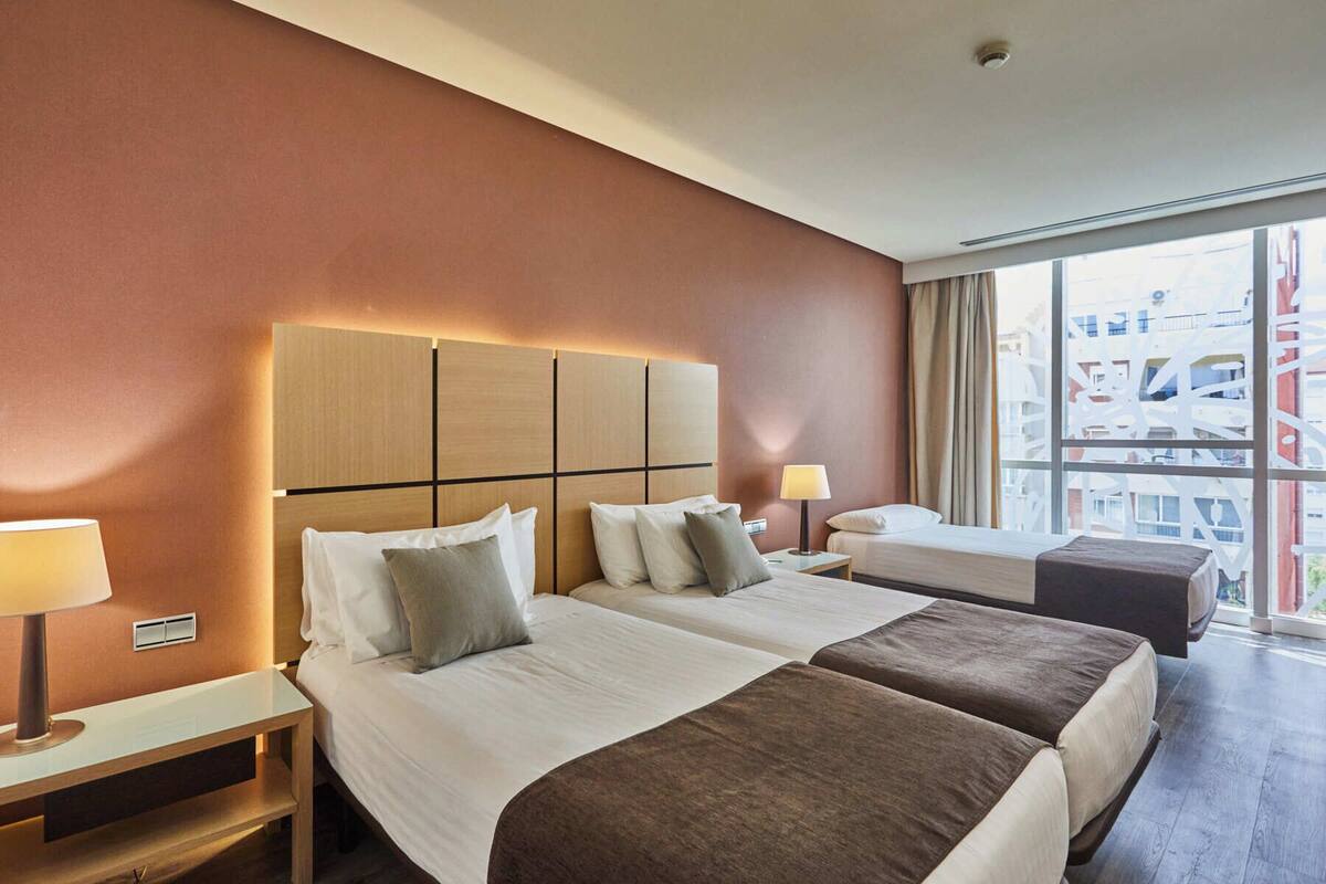Een hotelkamer met twee bedden, een groot raam en uitzicht op de stad.
