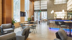 Een modern café met een bar, zitgedeelte en een duidelijke ingang naar het restaurant.