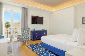 Een hotelkamer met een bed, een televisie, een dressoir, een stoel en uitzicht op gebouwen.
