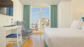 A hotel room with a bed, a desk, a chair, and a view of the outside.