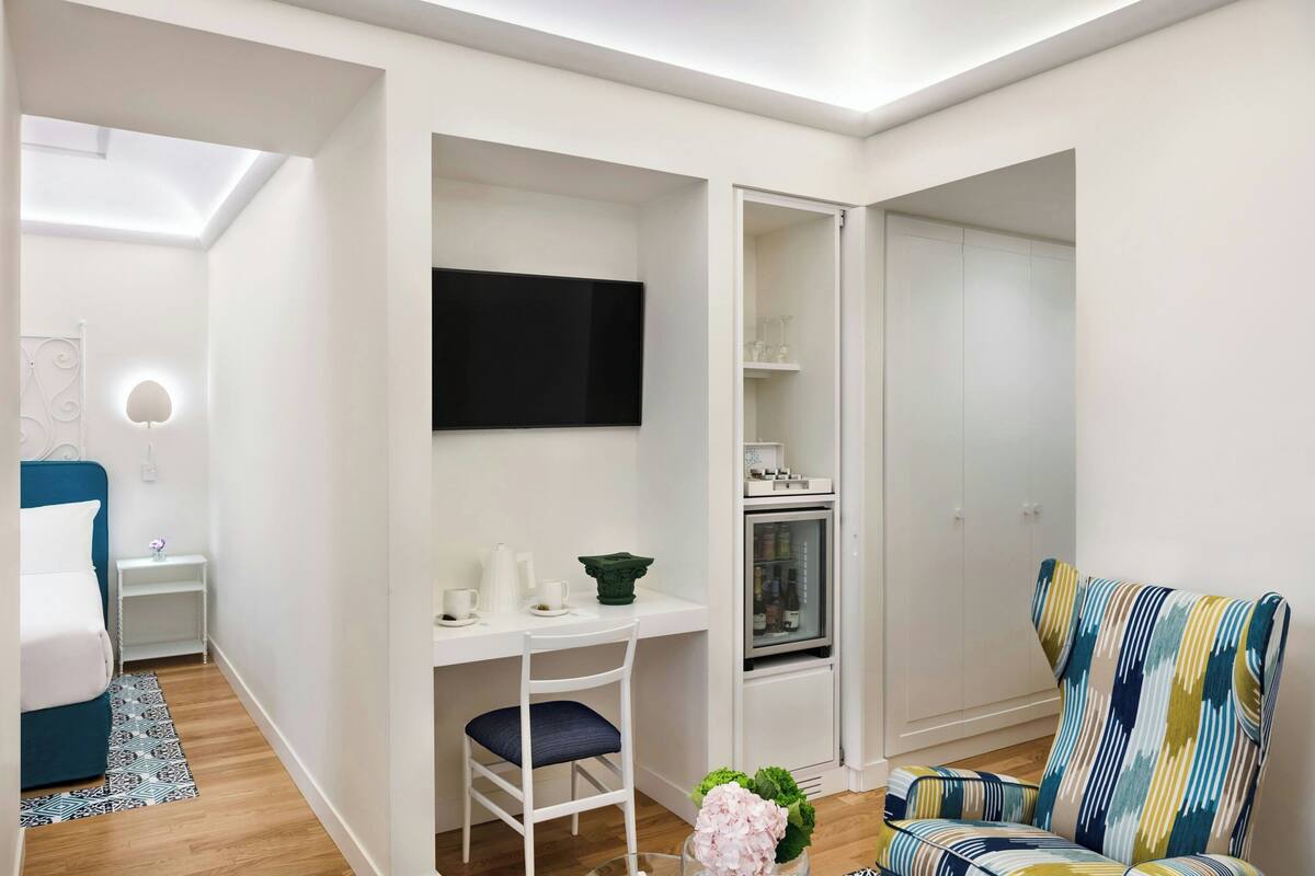 Un espace de vie moderne et compact, comprenant un bureau, une chaise et un fauteuil coloré.