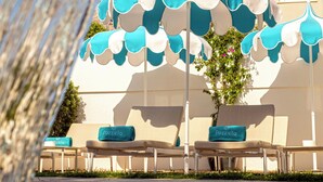 Un hôtel doté d’une terrasse avec des parasols, d’une piscine et d’un bâtiment avec des balcons.