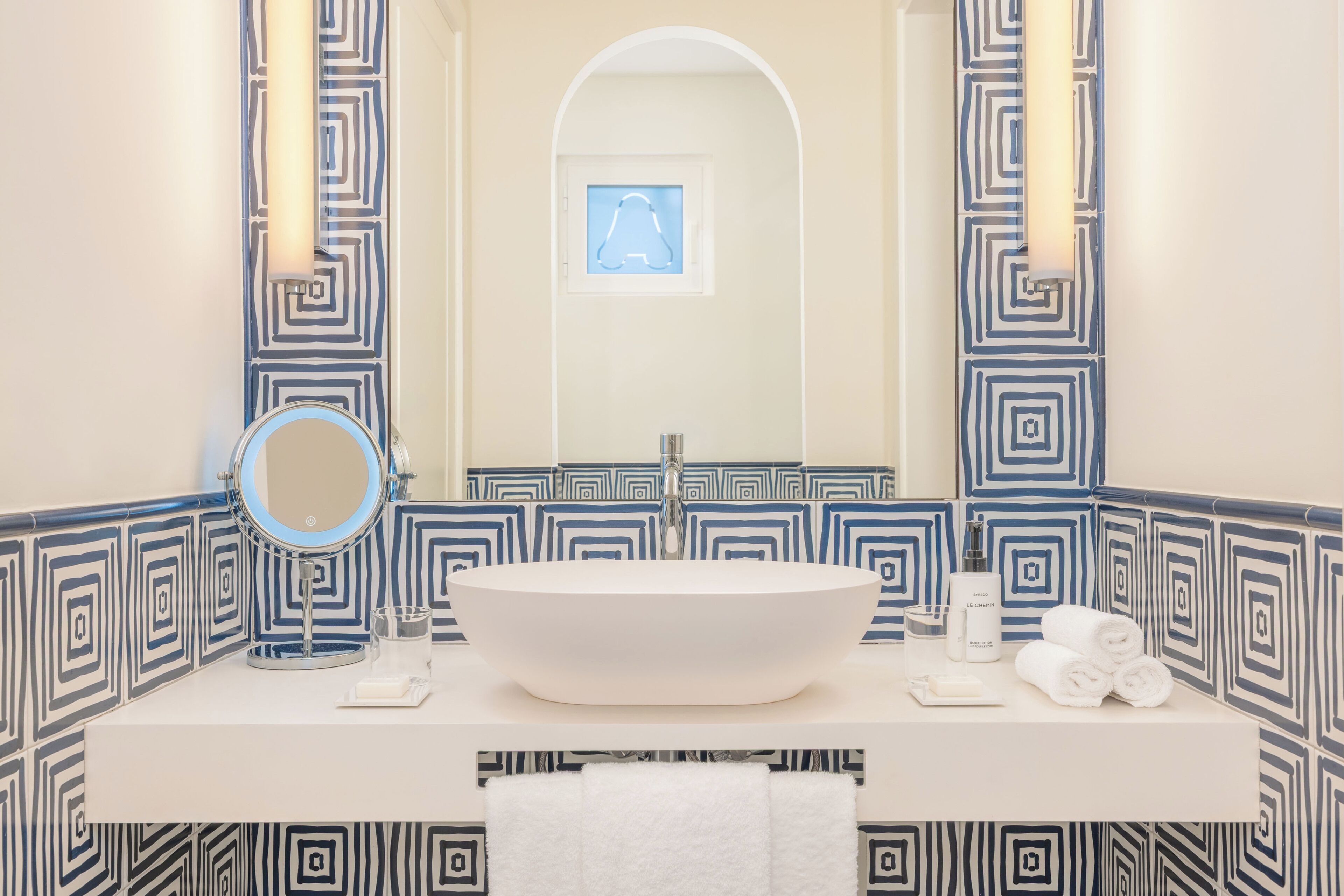 A bathroom with a large mirror, a sink, and a towel rack.