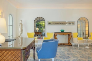 A room with a marble statue, a glass table, yellow chairs, a blue chair, and a decorative mirror. - Pazziella, a Luxury Collection Hotel, Capri (Capri)