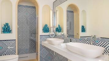 A modern bathroom with two sinks, a mirror, and decorative coral sculptures.