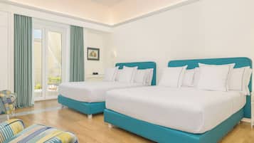 Habitación de hotel con dos camas, un sofá, una ventana con cortinas y vistas al exterior.