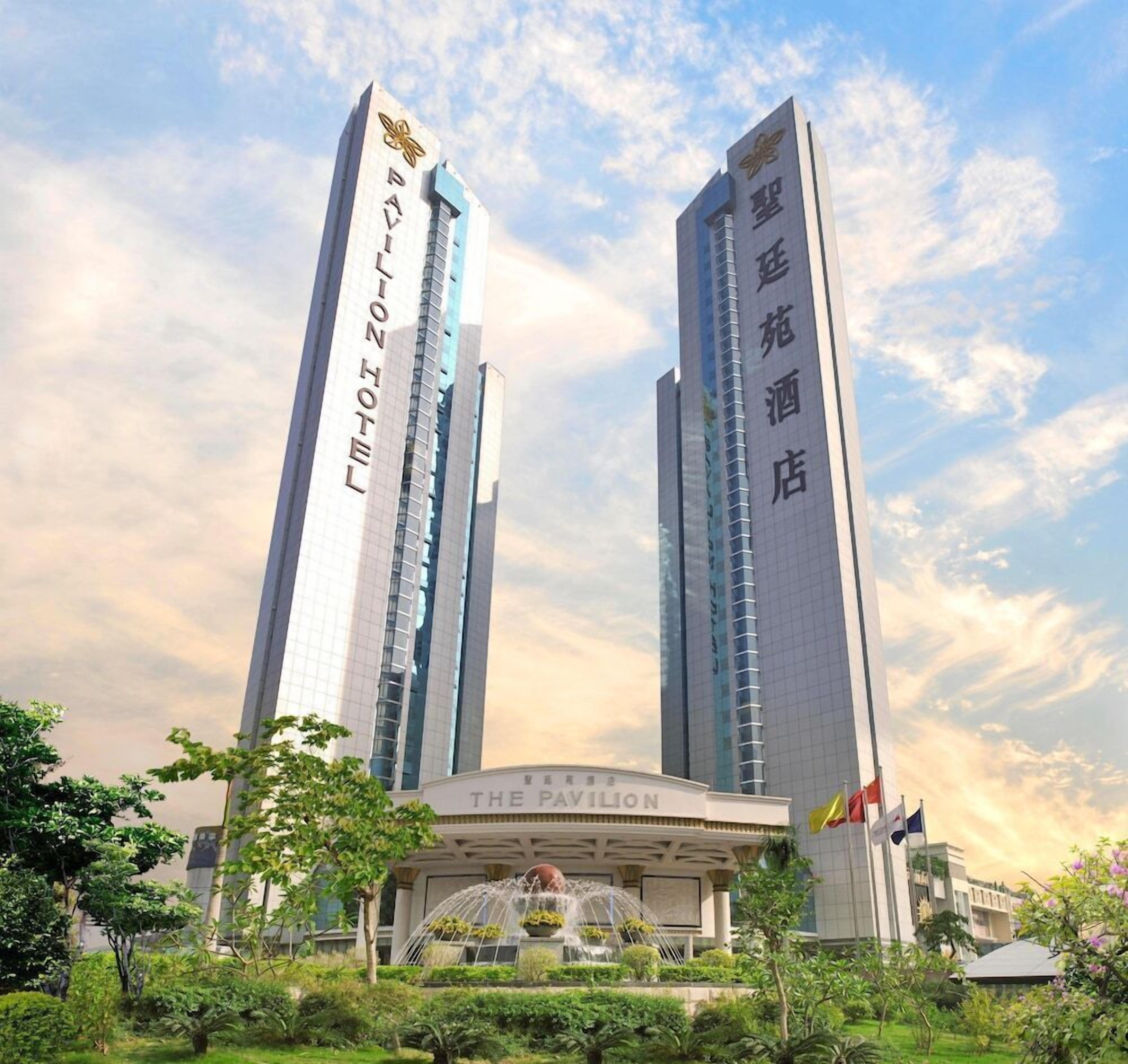 A hotel with two tall towers, a central entrance labeled 'The Pavilion,' and a fountain in the foreground.