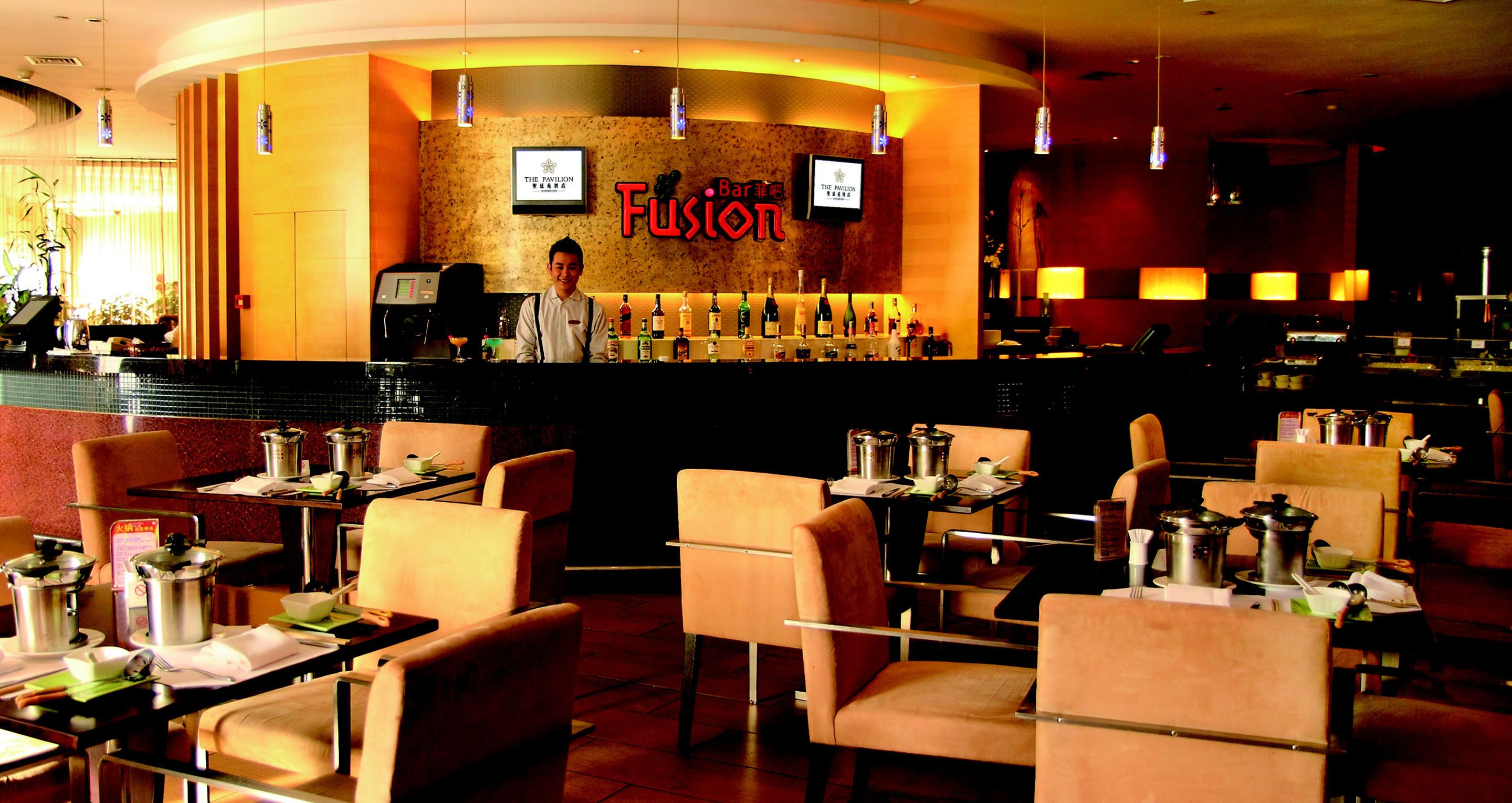 A restaurant with a bar area, multiple tables, and chairs.