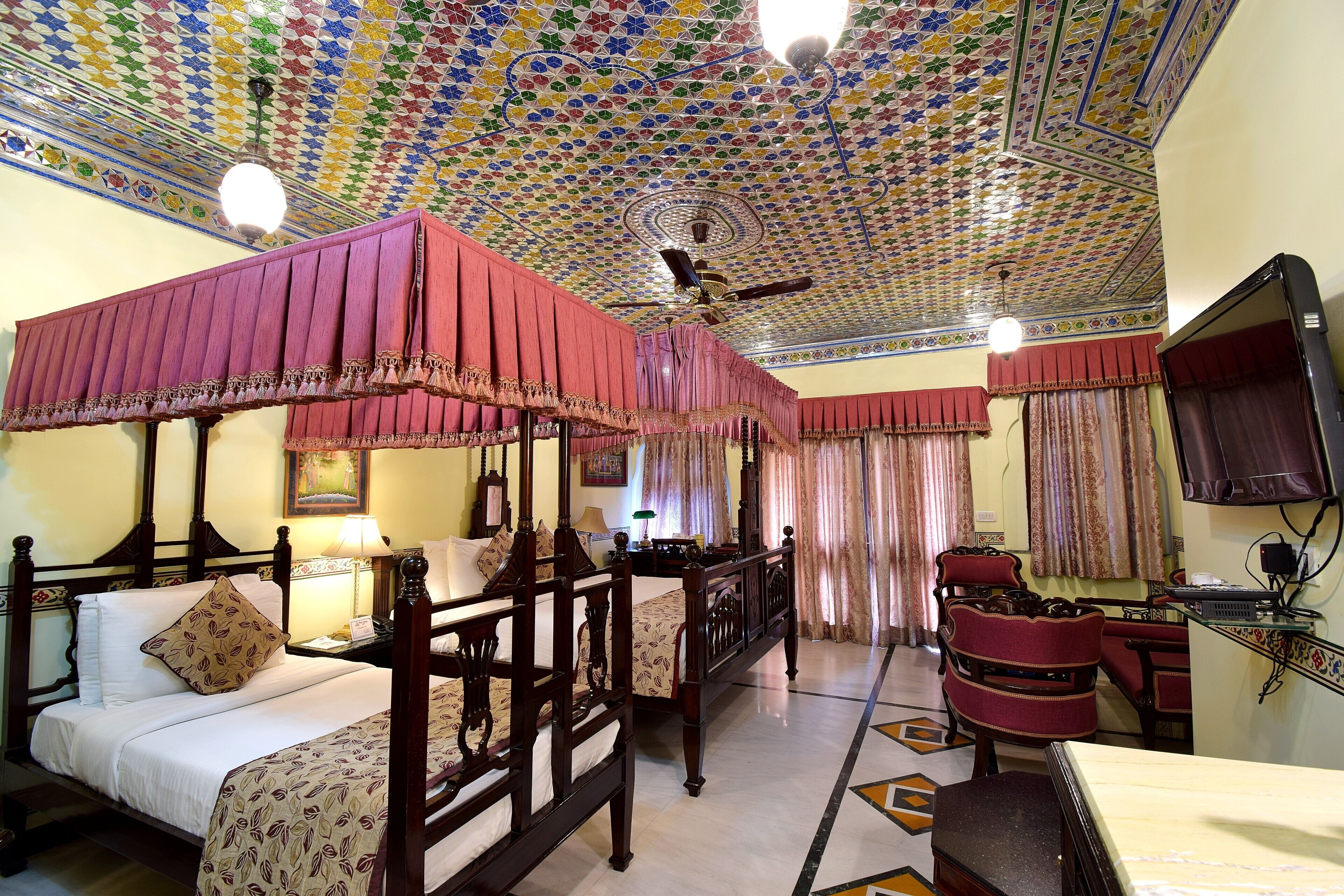 A traditional room with a four-poster bed, a desk with a computer, and a television.