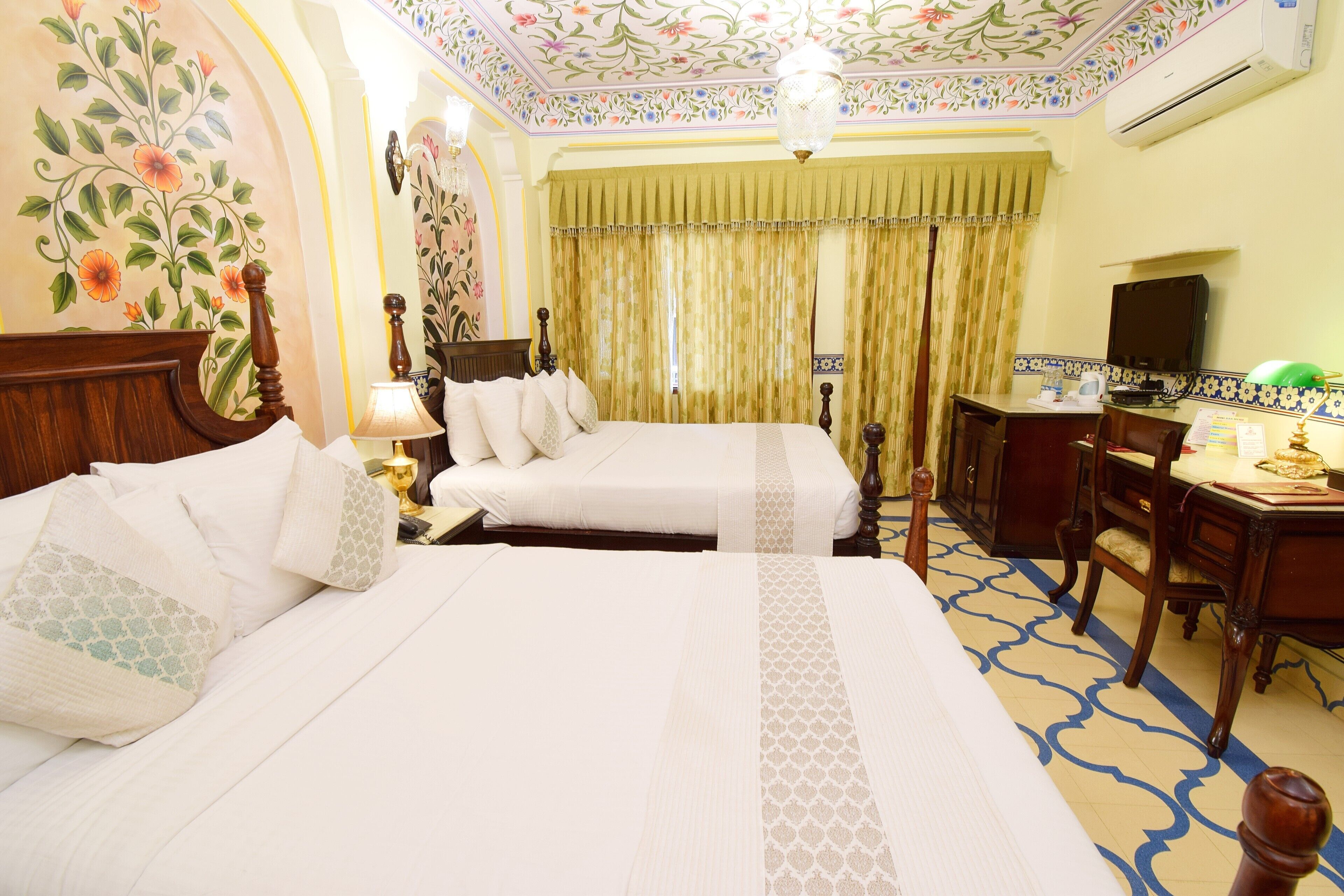 Une chambre d’hôtel avec deux lits, un bureau, une télévision et un lustre.