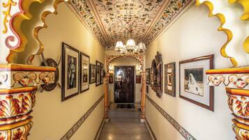 Um corredor com colunas ornamentadas, quadros nas paredes e um lustre.