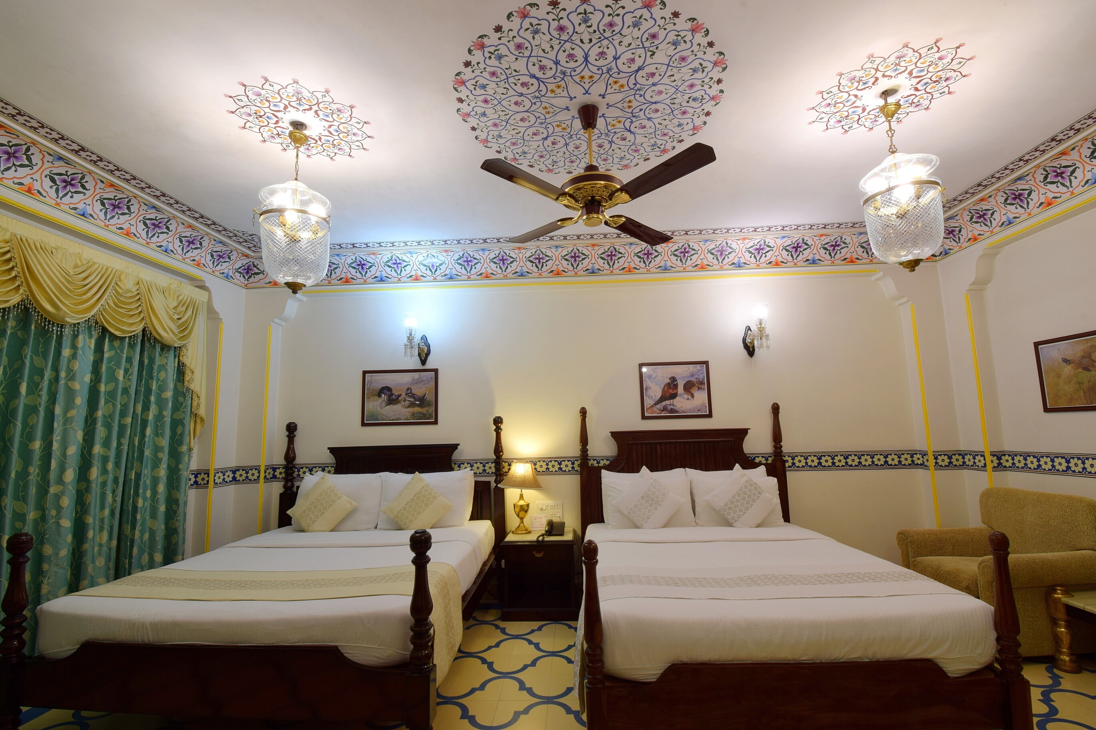 A room with two beds, a ceiling fan, and patterned walls.