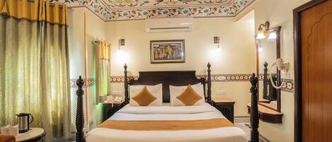 A neatly made bed with a wooden headboard, a ceiling fan, and a floral-patterned ceiling.