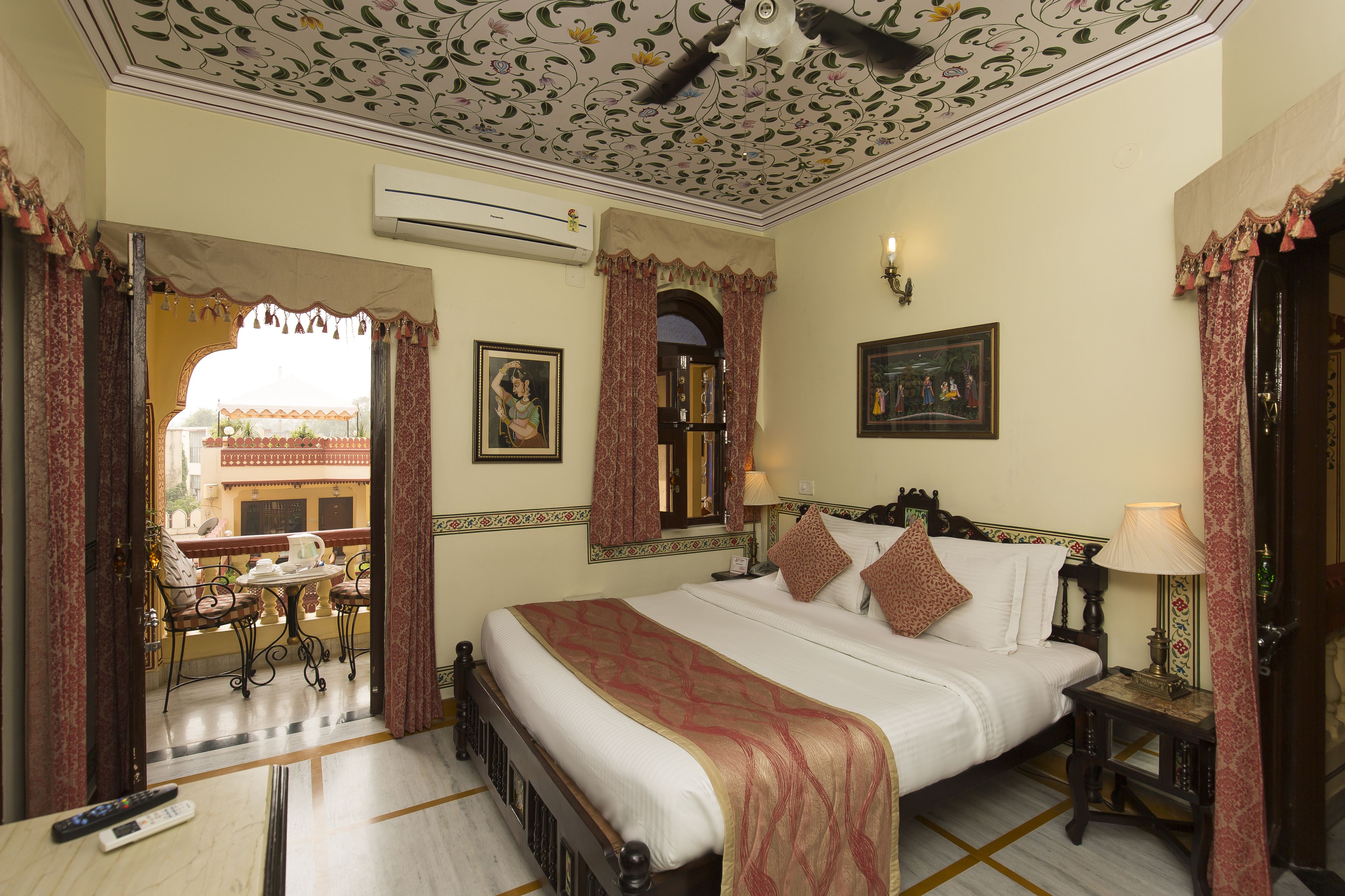 Une chambre d’hôtel avec un grand lit, une petite table, une chaise, un appareil de climatisation et une vue sur l’extérieur.