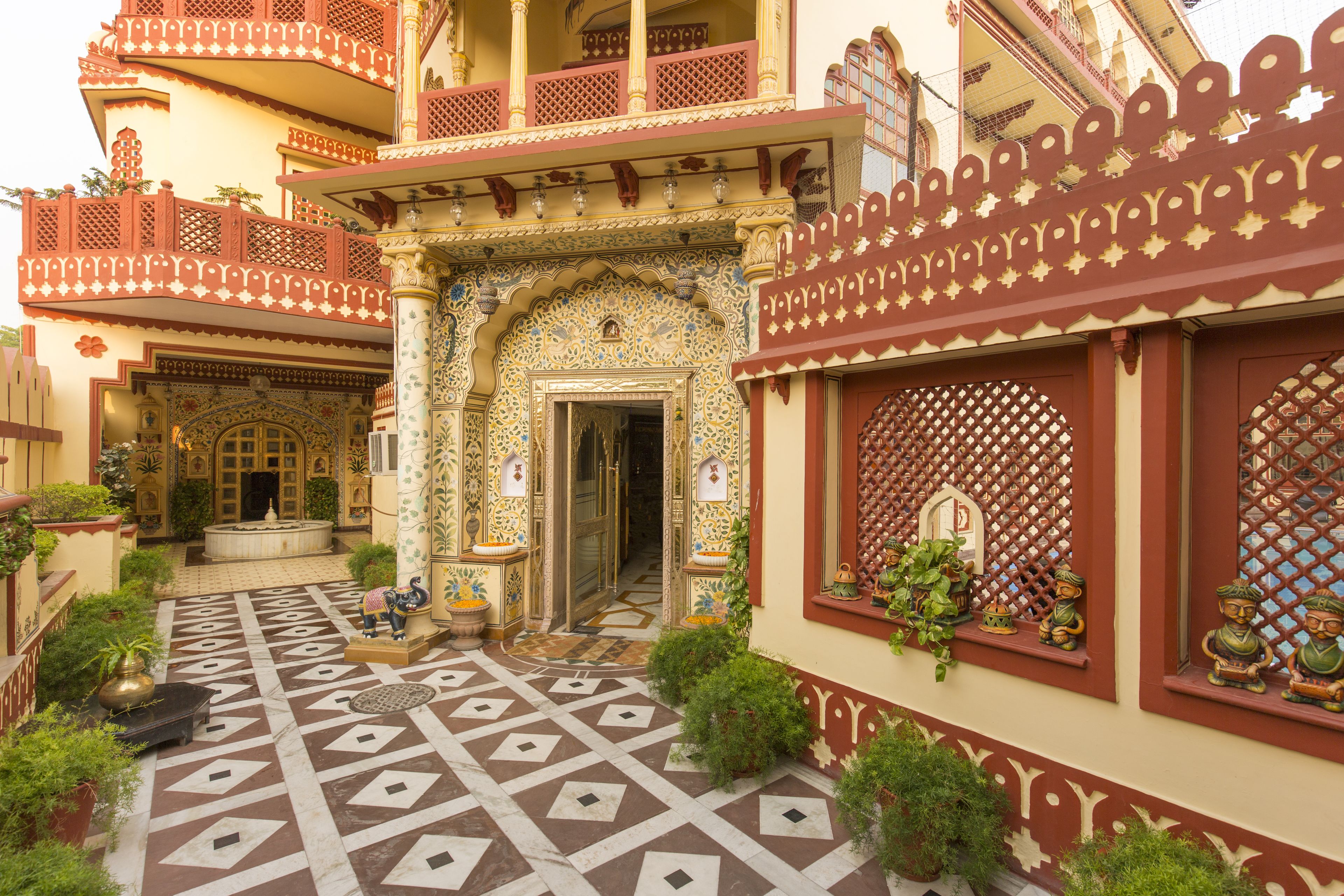 A courtyard with intricate tile work, a fountain, and a building with detailed balconies and windows.