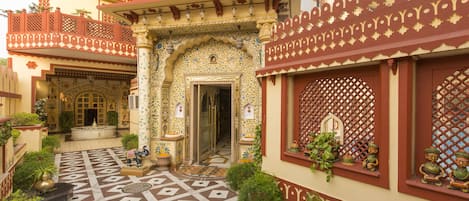 A courtyard with intricate tile work, a fountain, and a building with detailed balconies and windows.