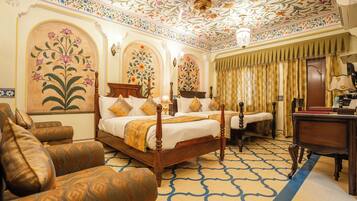 A traditional room with a four-poster bed, a desk, and a patterned carpet.
