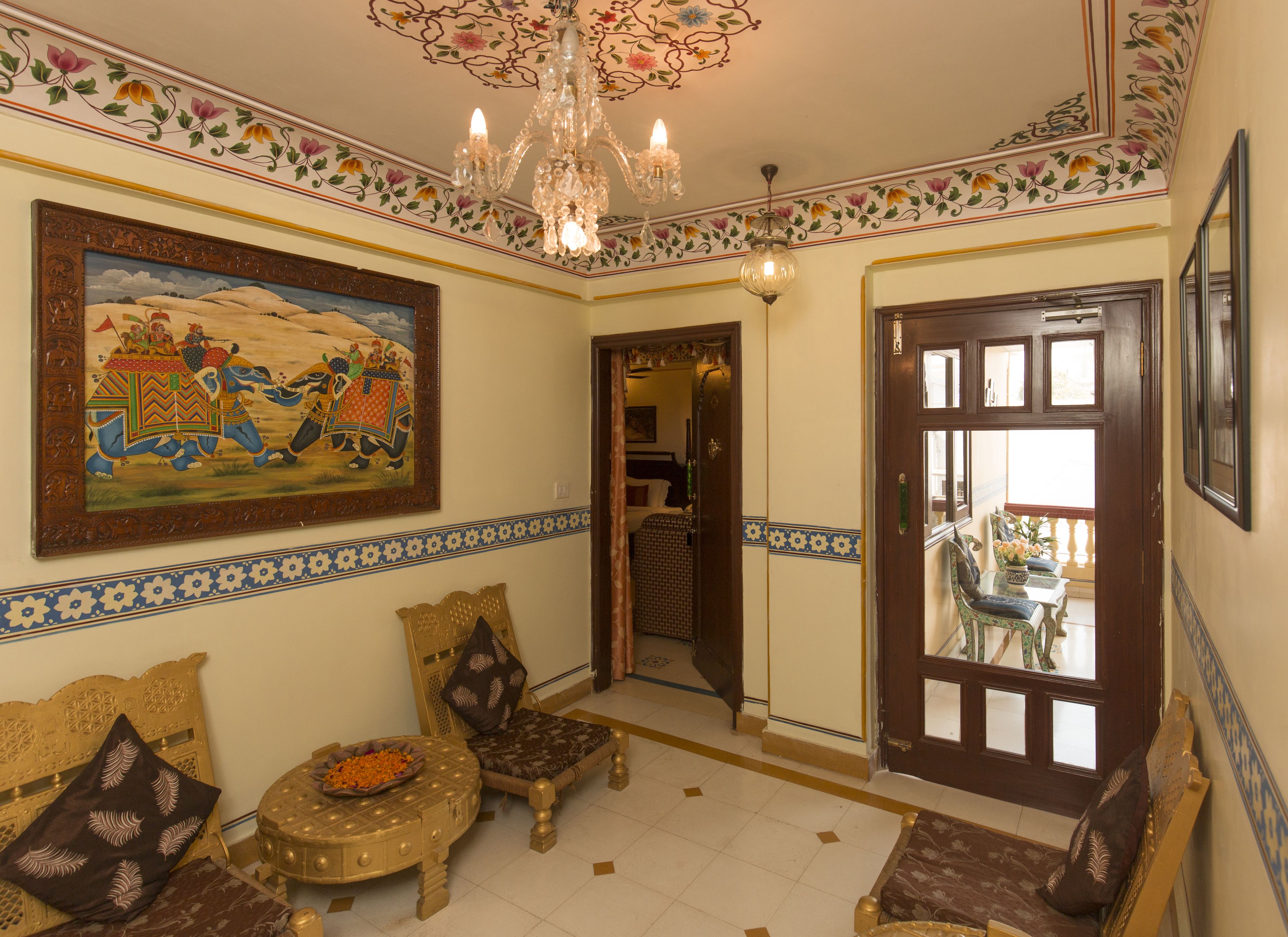 A traditional room with a chandelier, a painting, and a door leading to another room.