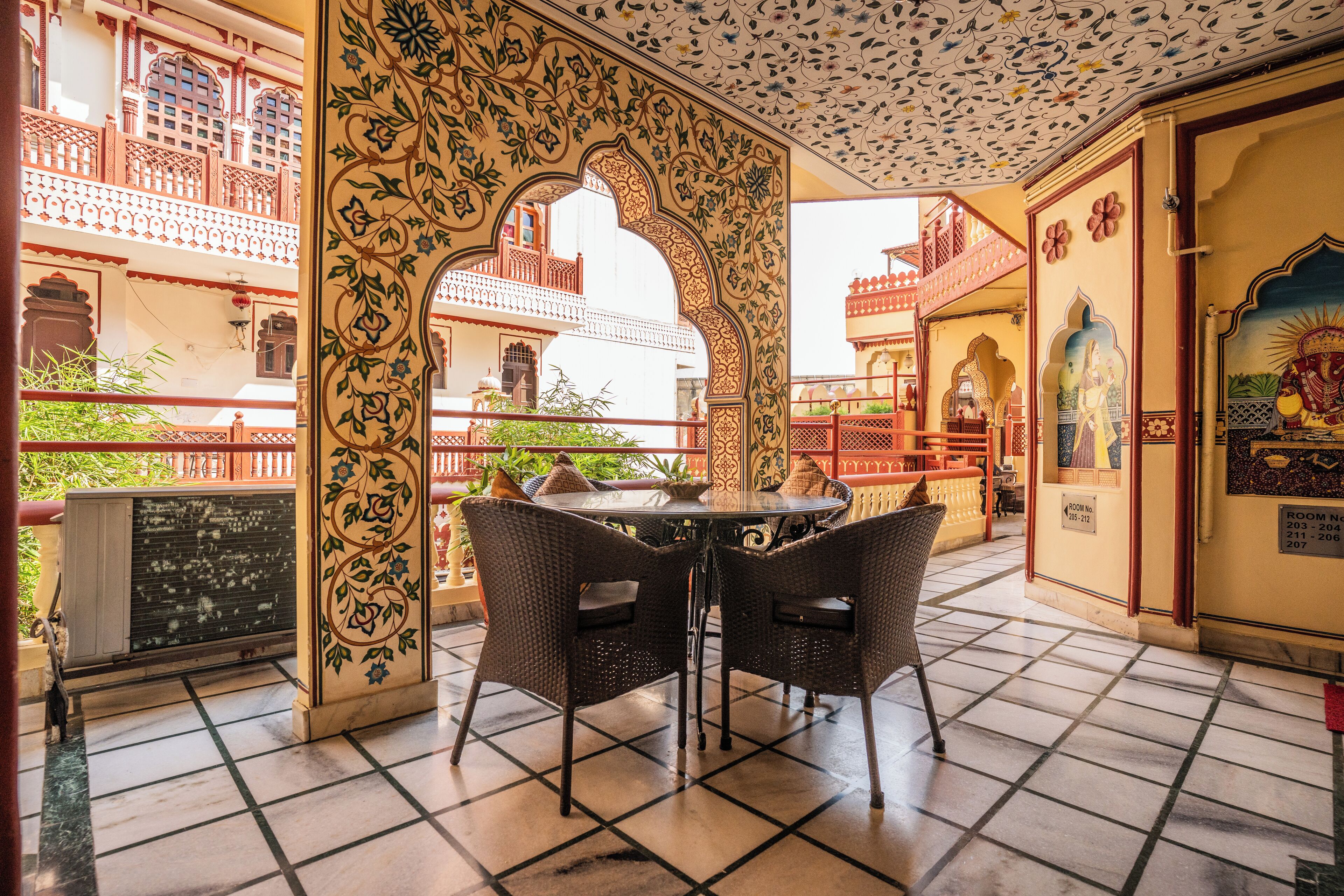A traditional courtyard with a tiled floor, a round table with chairs, and ornate architectural details.