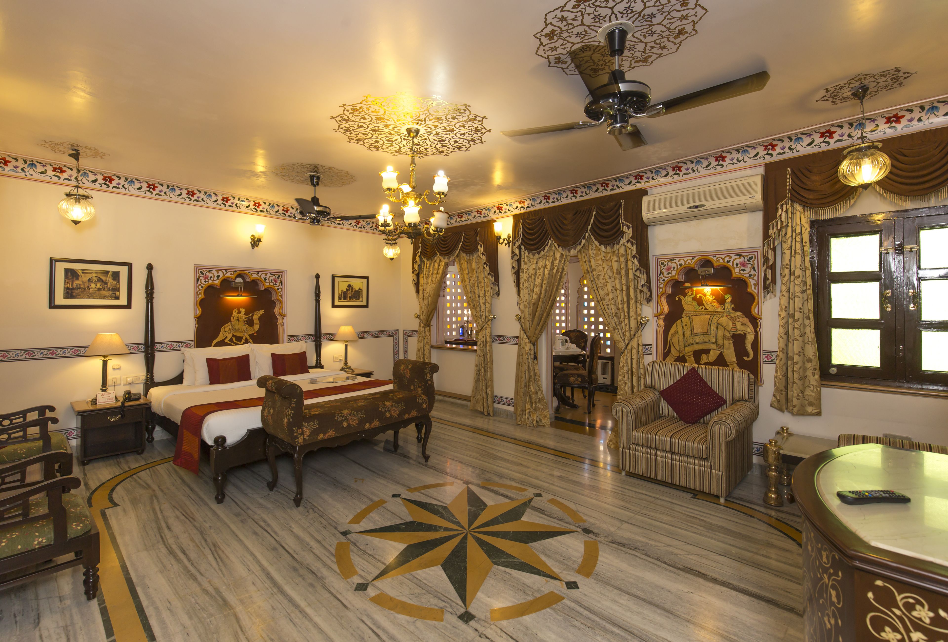 Una habitación tradicional con cama, sofá, mesa de comedor y lámpara de araña.