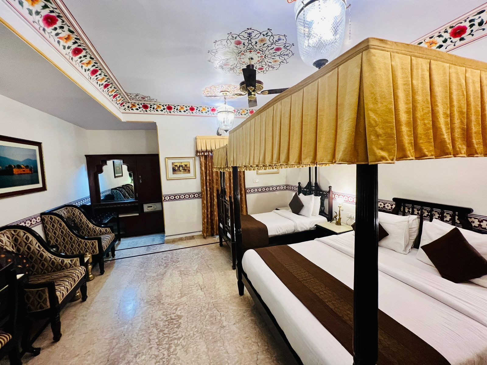 Une chambre d’hôtel avec deux lits, un bureau et un coin salon avec des chaises.