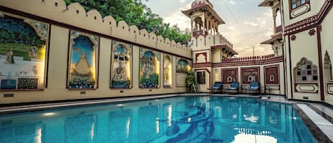 A swimming pool with a decorative wall and a small tower structure.