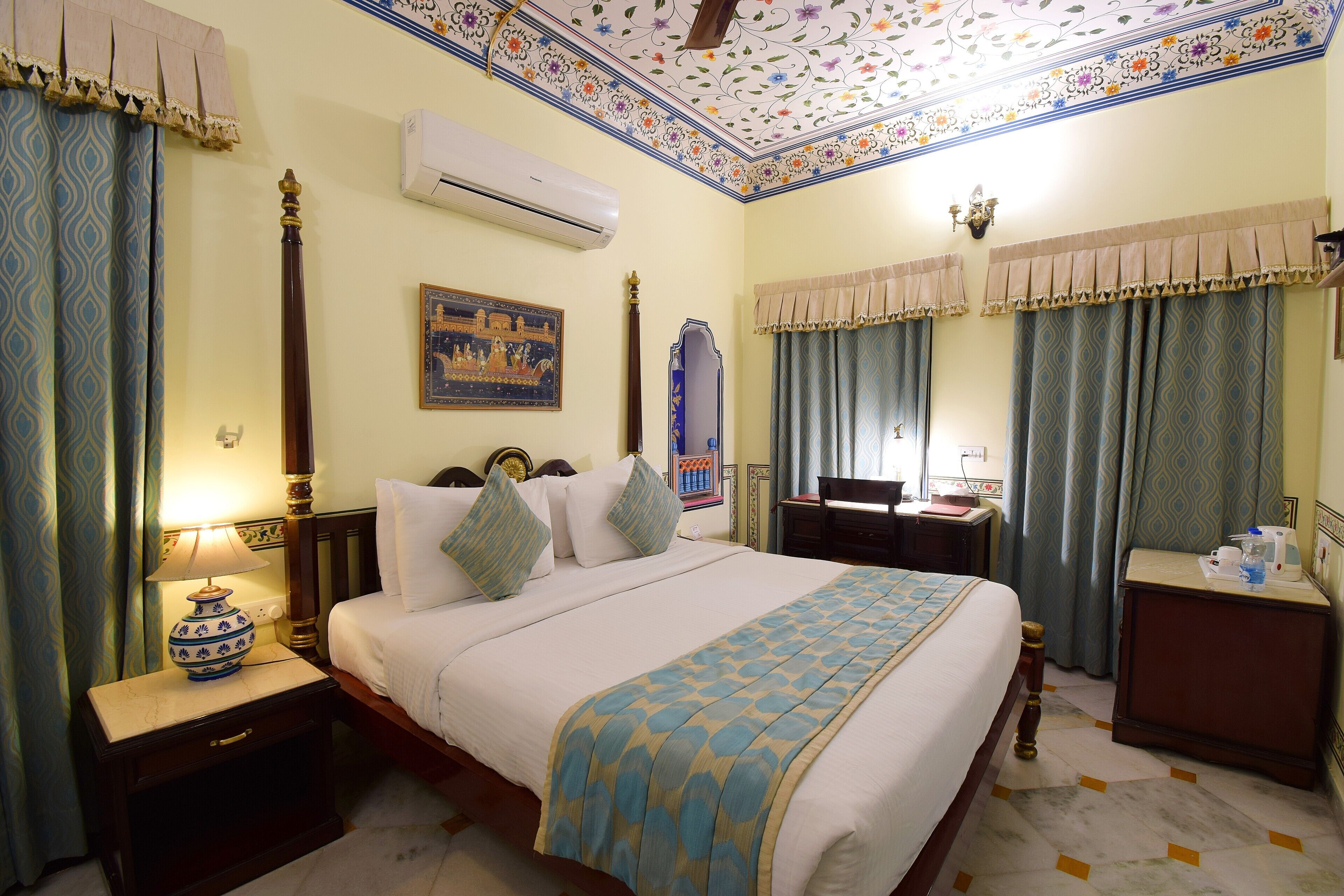Une chambre d’hôtel équipée d’un lit, d’une table de chevet, d’une lampe, d’un climatiseur et d’un plafond décoratif.