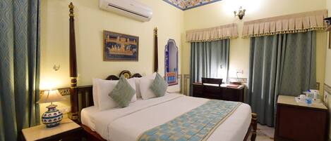 A hotel room with a bed, nightstand, lamp, air conditioning unit, and a decorative ceiling.