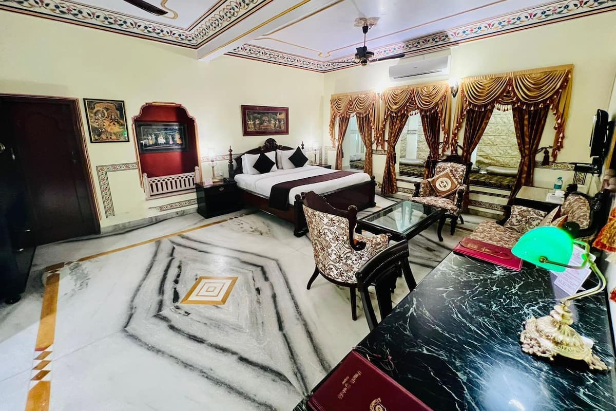 Une chambre d’hôtel comprenant un lit, une table à manger, des chaises, un ventilateur de plafond et des éléments décoratifs sur les murs et le sol.