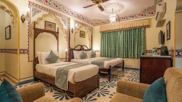 A traditional room with two beds, a ceiling fan, and patterned floor tiles.