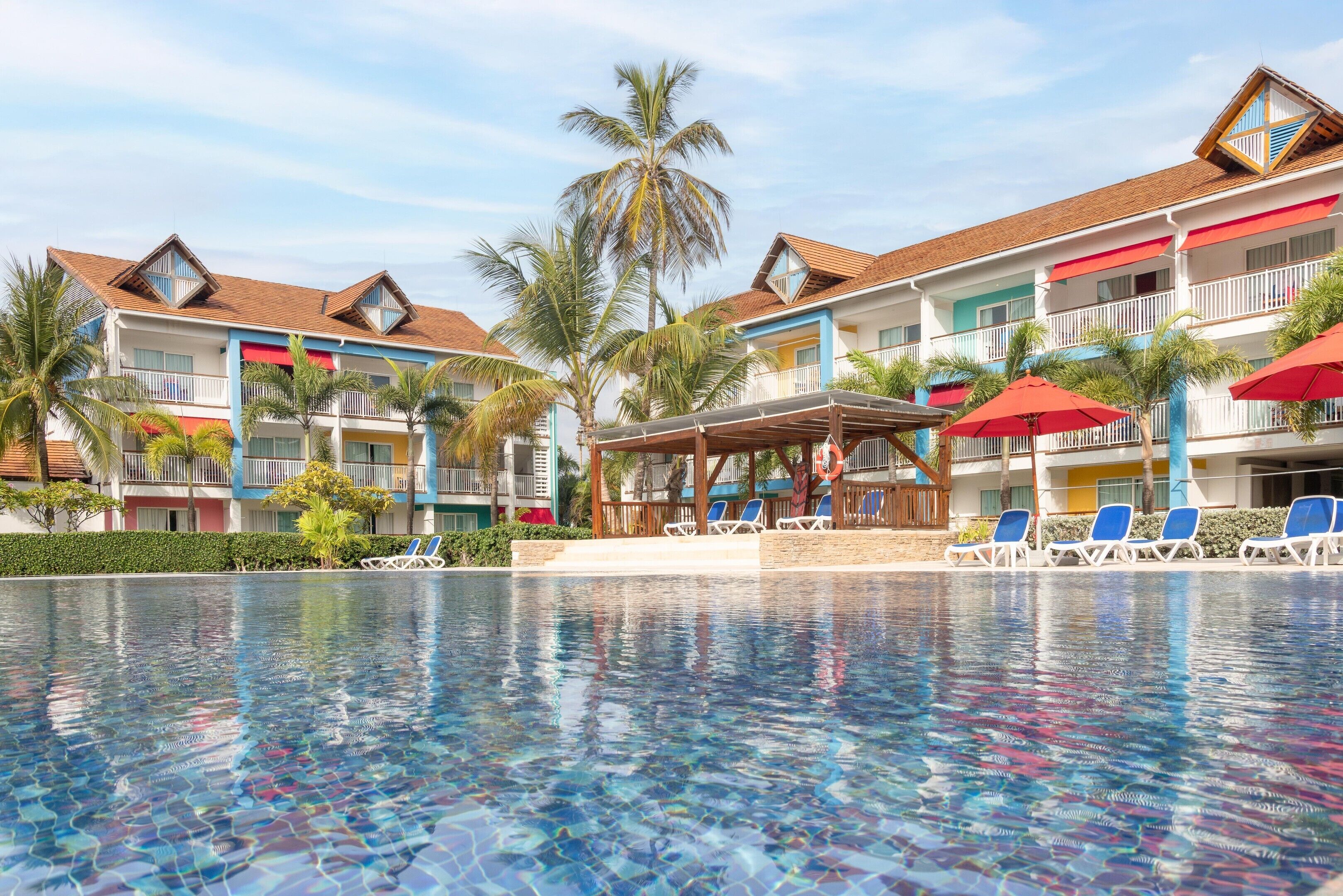 Un hotel con varios balcones, piscina y palmeras.