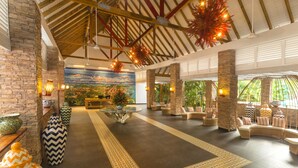 A spacious lobby with a high ceiling, stone pillars, and a central seating area with sofas and a coffee table.