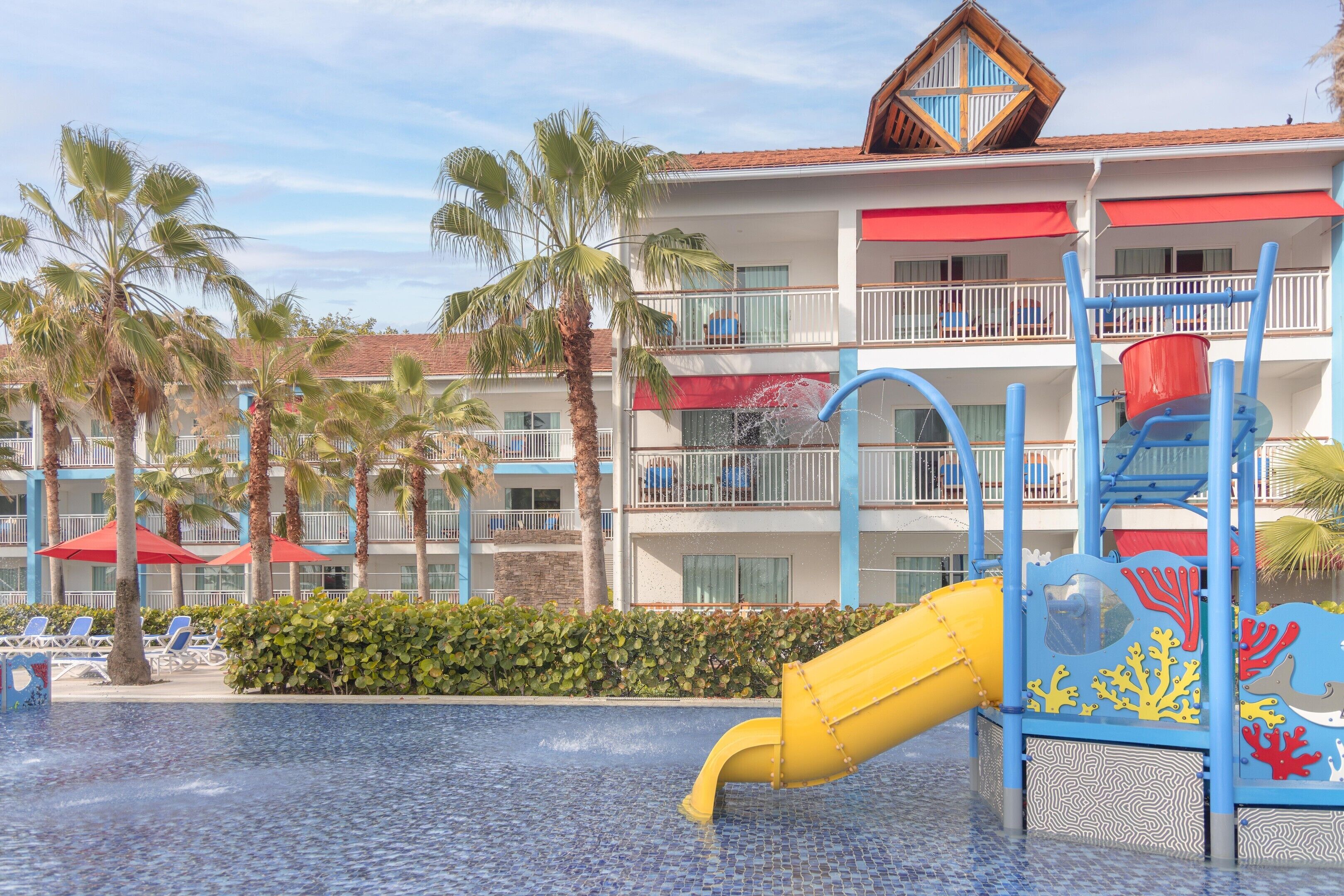 Un hotel con zona de piscina que incluye un tobogán y una estructura de juegos.