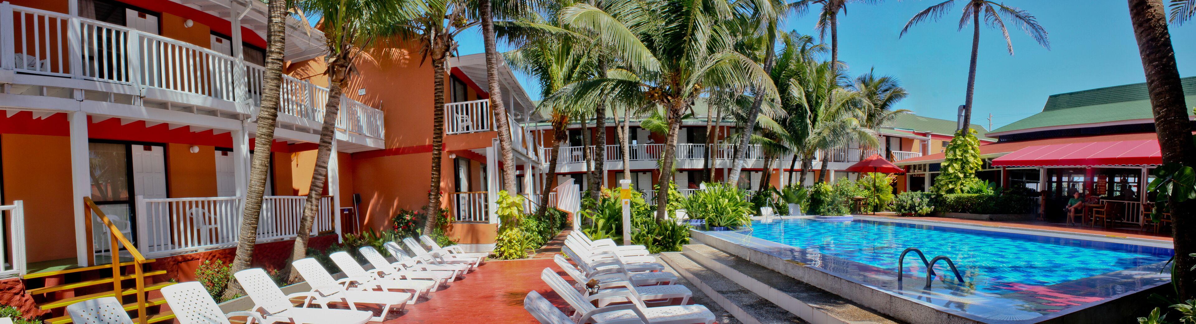 A hotel with a swimming pool, lounge chairs, and palm trees.