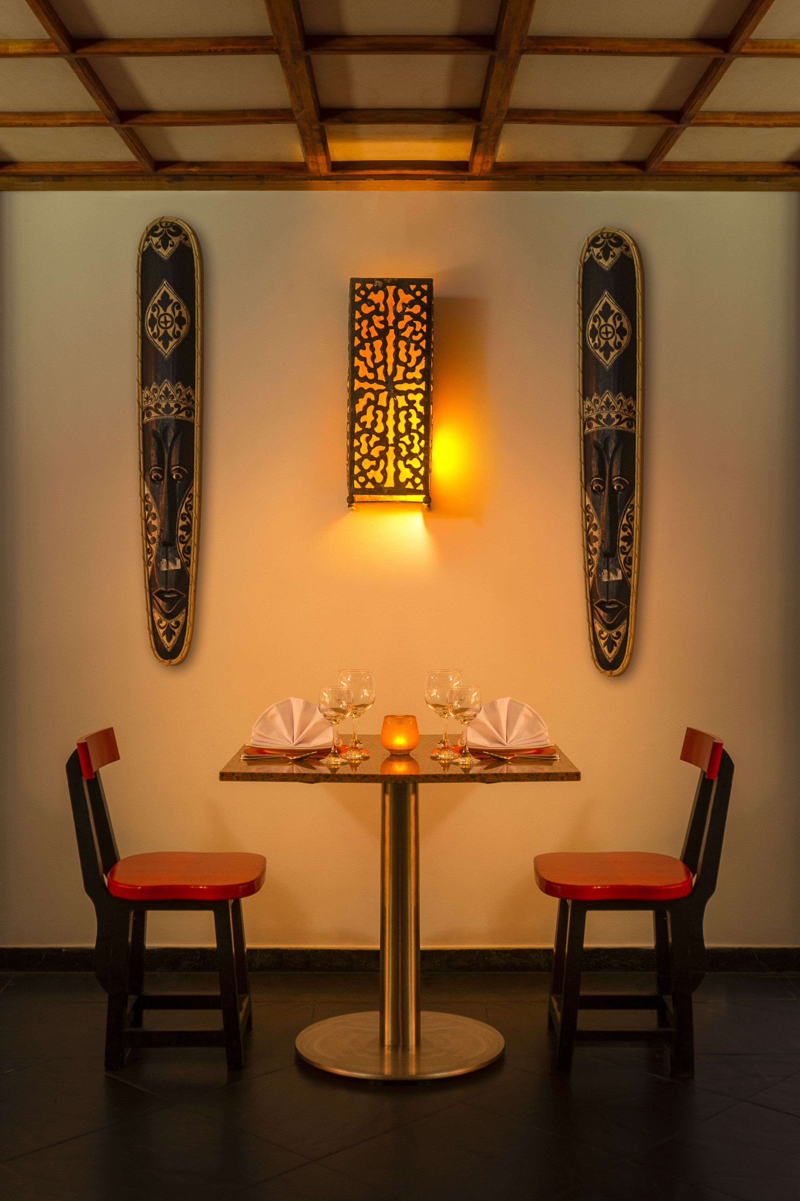 A dining area with a round table, two chairs, and a wall-mounted light fixture.