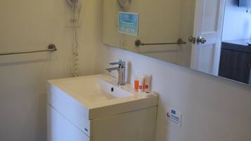 A bathroom with a white sink, a mirror, a hand dryer, and a toilet.