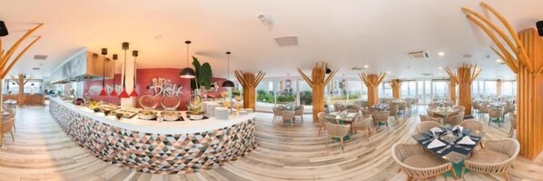 A spacious hotel lobby with a central reception area, multiple seating arrangements, and large windows providing natural light.