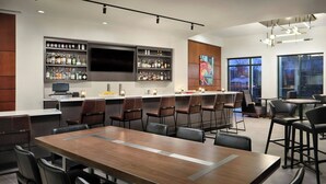 A modern bar area with a long counter, multiple seating options, and a large TV screen.