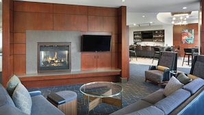 A modern lounge area with a fireplace, comfortable seating, and a bar in the background.