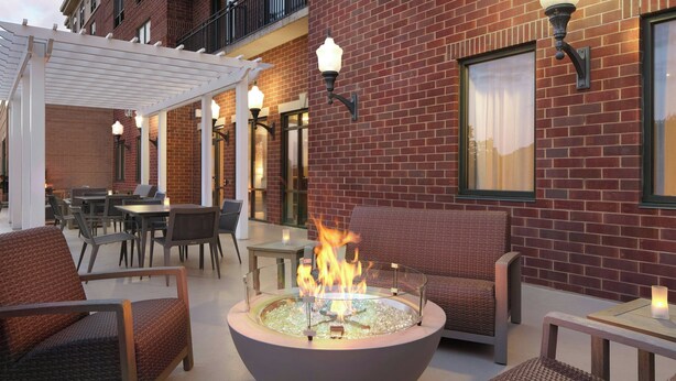 An outdoor seating area with a fire pit, wicker furniture, and brick walls.