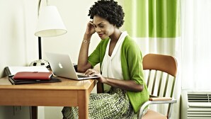 A person sitting at a wooden table with a laptop, a lamp, and a red notebook. - Fairfield Inn & Suites by Marriott Indianapolis Noblesville (Noblesville)