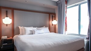 A hotel room with a large bed, two bedside lamps, a nightstand with a phone, and a window with curtains. - Fairfield Inn & Suites by Marriott Indianapolis Noblesville (Noblesville)