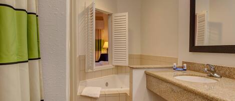 A bathroom with a bathtub, a sink, and a mirror.